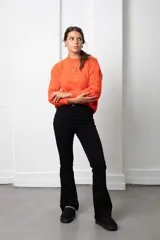 Buzo de lana color coral con diseño de tejido trenzado, cuello redondo y mangas largas.