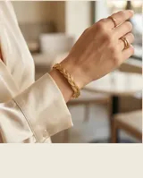 Esclava abierta de acero con baño de oro, con diseño trenzado en relieve.