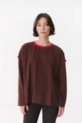 Remera de manga larga con corte oversized, color azul marino con cuello redondo en contraste color marrón. Presenta costuras decorativas a contratono hechas a mano en la zona de los hombros y logo bordado en el centro del pecho.