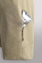 Pantalón corto de estilo técnico, color beige, con ajuste regular. Cuenta con cintura ajustable mediante cinturón de doble hebilla, cierre frontal con cremallera y botón a presión, bolsillos laterales y bolsillos con cremallera oculta.