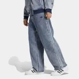 Jeans de mezclilla Adidas de pierna recta, efecto acid wash, con corte holgado, tiro medio y las clásicas tres tiras laterales. Cuenta con bordado del trébol de la marca.