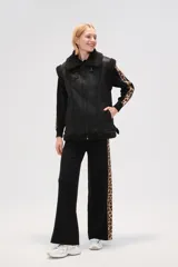 Chaleco de estilo aviador en color marrón, confeccionado en material tipo cuero con interior y bordes de corderito sintético en color crema. Presenta cierre frontal, cuello alto con tira de ajuste y bolsillos laterales.