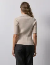 Buzo azul de tejido acanalado, con cuello solapa y escote en V en tejido calado.