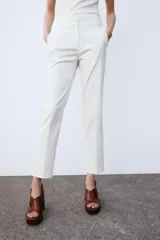 Pantalón de tiro medio con cintura elástica en la parte posterior. Cuenta con bolsillos delanteros, falsos bolsillos de vivo en la parte trasera y aberturas laterales en el bajo. Cierre frontal con cremallera, botón interior y gancho.