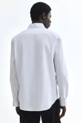 Camisa de vestir H&M de corte entallado, confeccionada en tejido elástico de mezcla de algodón. Presenta cuello italiano, cierre frontal de botones y mangas largas con puños ajustables.