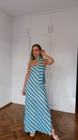 Vestido largo sin mangas, con escote palabra de honor y pañuelo incorporado al cuello. Presenta un estampado geométrico en tonos celeste, verde y blanco, con aberturas laterales en la falda.