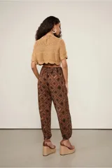 Pantalón babucha de viscosa con estampado geométrico en tonos marrones. Tiene cintura alta con detalle de nudo en el frente, forro corto y terminación ajustada en el bajo.