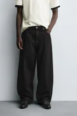 Jeans de denim de algodón color negro, con corte balloon fit relajado desde la cadera y ligeramente estrechado en el bajo. Tiro medio, cinco bolsillos y cierre frontal con cremallera y botón.