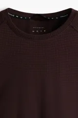 Remera deportiva color marrón oscuro con tecnología DryMove, de manga corta raglán, cuello redondo y paneles microperforados en los laterales y hombros.