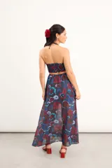 Vestido largo de gasa con estampado floral acuarelado en tonos azules y rojos, con escote halter, tiras regulables y detalles cut out en la cintura y el escote con apliques de cuentas.
