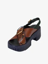 Sandalias de cuero con plataforma, tiras cruzadas y hebilla metálica.