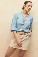 Minifalda de jean color beige claro, con corte en A y bolsillos delanteros curvos.