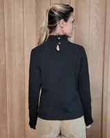 Polera de manga larga color blanco, confeccionada en algodón, con cuello alto tipo tortuga y detalles de volados en el cuello y en los puños.