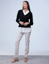 Buzo combinado con torso de tejido de punto fino en color negro y detalles de cuello y ruedo en gasa blanca que simulan una camisa debajo. Presenta escote en V y mangas largas.