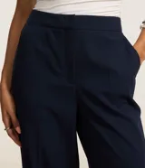 Pantalón de corte recto y estilo sastre, color azul marino, con bolsillos laterales tipo cuchillo y cierre frontal.