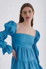 Vestido corto blanco de lino, con escote recto, mangas abullonadas 3/4 con elástico y falda con volado.