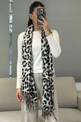 Bufanda rectangular con estampado animal print en tonos blanco y negro, con terminaciones de flecos en los extremos.