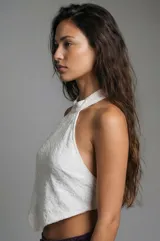 Top blanco con cuello halter y diseño en punta tipo pañuelo. Confeccionado en tejido con textura, sin mangas y con espalda descubierta.