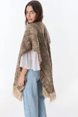Ruana artesanal tejida en telar con lana hilada a rueca por tejedoras rurales de Uruguay. Diseño con patrón a cuadros en tonos marrón y crudo, con flecos en los extremos.