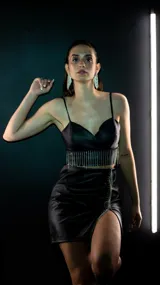 Top negro de simil cuero con breteles finos, escote en V y flecos de strass en el ruedo.