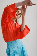 Blusa color naranja con escote mao y abertura frontal con botones. Mangas tres cuartos con detalles fruncidos.