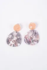Aros colgantes con diseño de dos piezas, una circular superior en tono durazno y una pieza inferior de forma irregular con efecto marmolado en tonos gris, blanco y rosado.