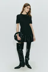 Vestido corto de punto con escote redondo y mangas cortas. Presenta un diseño entallado en el cuerpo y una falda con volado inferior confeccionado en tela satinada con brillo.