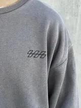 Buzo gris de corte oversize con cuello redondo y puños ajustados. Estampado en la espalda con la palabra "UNEXPECTED" y la frase "JOIN THE ROAD - POWER CONNECTION".