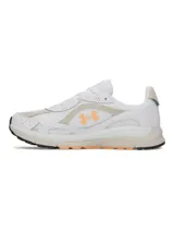 Championes deportivos Under Armour modelo Tech Runner, con diseño de perfil bajo. Presentan una parte superior de malla transpirable en color blanco con superposiciones de cuero y gamuza en tonos beige. Incluyen detalles en color naranja, destacando el logotipo de la marca en el lateral, y una entresuela de EVA acolchada con suela de goma.