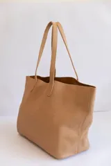Bolso tote de cuero color tostado, con doble asa de hombro y diseño minimalista. Incluye un bolsillo separador extraíble.
