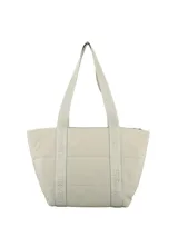 Bolso tipo tote color beige, confeccionado en lona capitoneada con diseño acolchado. Cuenta con dos asas largas de cinta con el nombre de la marca estampado y un amplio compartimento principal forrado en su interior.