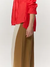 Camisa de lino liviano color tostado, con silueta relajada, cuello mao, alforzas verticales frontales, mangas con volumen y puños elastizados con volados.
