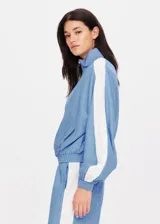 Chaqueta con cremallera color celeste con paneles blancos en las mangas.