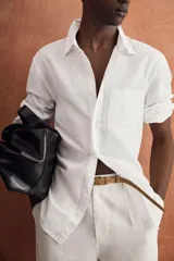Camisa azul de corte regular fit confeccionada en tejido de lino y algodón, con cuello abotonado, manga larga, bolsillo aplicado en el pecho y cierre frontal con botones.