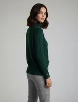 Polera de tejido fino, color rosado, con cuello alto, manga larga y detalle de tajo en los puños.