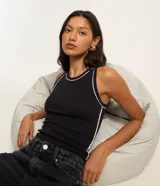 Musculosa de rib en color negro, con diseño ajustado al cuerpo, cuello redondo y frisos contrastantes blancos en el escote y las sisas.