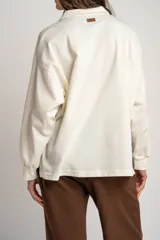 Sweater de tejido de punto con diseño a rayas horizontales en color crema y marrón. Presenta cuello tipo polo con cierre frontal de botones ocultos, mangas largas y un corte oversize.