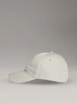 Gorra de béisbol color beige claro con logo de Calvin Klein bordado en blanco en el frente.