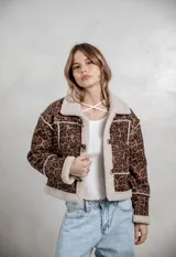 Campera de gamuza con estampado de leopardo en tonos grises, con interior y bordes de corderito sintético color crema. Presenta cierre frontal con botones tipo toggle y diseño de corte recto.