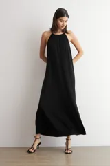 Vestido largo negro de lurex, con escote halter y diseño fluido y acampanado.
