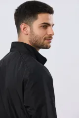 Campera liviana de nylon color azul marino, con cuello alto, cierre frontal y puños y dobladillo en elástico tejido.
