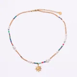 Collar tipo gargantilla con cadena dorada ajustable, intercalada con cuentas de semillas multicolores y perlas blancas. Incluye un dije colgante dorado con forma de sol radiante.