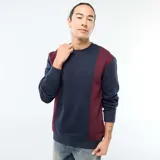 Buzo de cuello redondo con diseño color block en azul marino y bordó. Presenta un estampado minimalista en el pecho y puños acanalados.