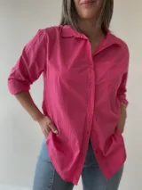 Camisa celeste de corte holgado, con cuello clásico, cierre frontal con botones, bolsillo en el pecho y mangas largas con puños abotonados.