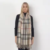 Bufanda rectangular color beige con estampado de cuadros grandes en negro, blanco y rojo. Tiene flecos en los extremos.