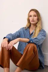 Camisa de jean oversized color azul, con botones rojos y costuras en contraste rojo. Tiene un bolsillo en el pecho.