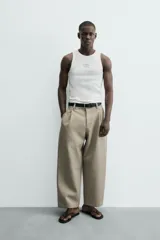 Camiseta tipo tank (sin mangas) de corte relaxed fit, color blanco, con cuello redondo y un pequeño estampado gráfico en el pecho que dice "SANTA BARBARA EST. 1987 CALIFORNIA".