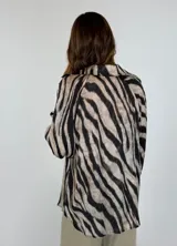 Blusa azul con estampado de cebra en negro, escote en V y mangas largas abullonadas.