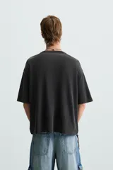 Camiseta boxy fit de punto tejido en hilatura de algodón, color negro con efecto lavado. Cuello redondo y manga corta. Estampado frontal con letras en blanco y verde.