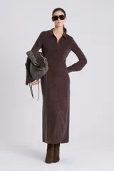 Vestido camisero largo color marrón oscuro, con cuello y botones frontales. Presenta mangas largas y puños anchos.